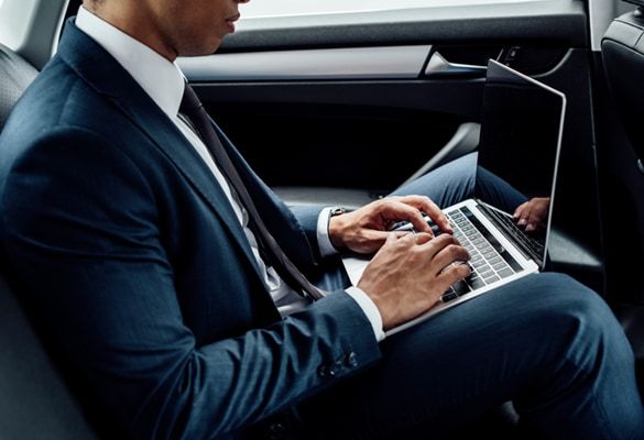 Homme d’affaires en costume travaillant sur son ordinateur portable à l’arrière d’une voiture